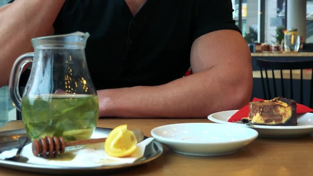 A man sits at a table with meal in a cafe and drinks tea - closeup on the table