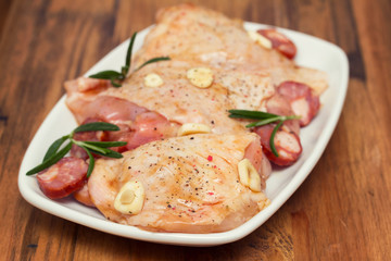 raw marinated chicken with smoked sausage on white dish