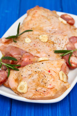 raw marinated chicken with smoked sausage on white dish
