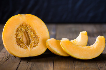 Half melon and slices on a dark wooden background
