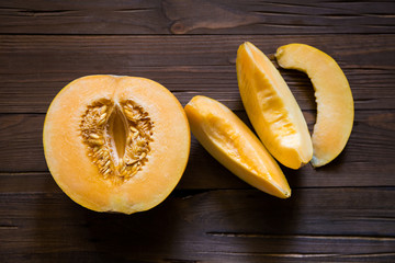 Half melon and slices on a dark wooden background