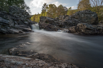 Little waterfall in front of trees with warm light.