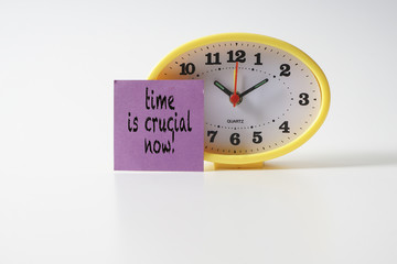 Yellow table clock with time management conceptual text on the note.