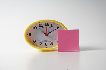 Yellow table clock with time management conceptual text on the note.