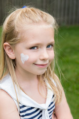 adorable school age girl with sunscreen in heart shape on face outside in summertime