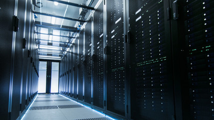 Shot of a Working Data Center With Rows of Rack Servers. People Walk and Work there, they are...