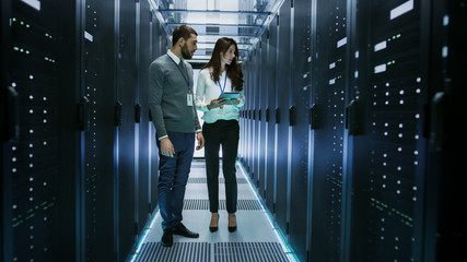 Female and Male IT Engineers Discussing Technical Details in a Working Data Center/ Server Room.