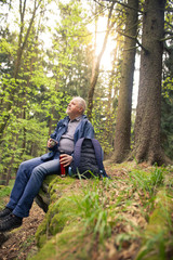 Naklejka na ściany i meble Senior man relaxing during the trip in the forest, rest time, drinking home-tea