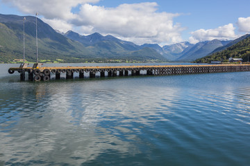 Obraz premium Long urban pier at norwegian fiord with the picturesque mountain landscape