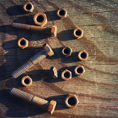 Old rusty bolts and nuts on a wooden surface 