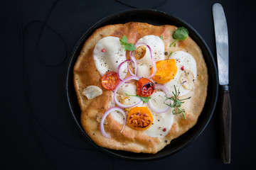 Small homemade pizza with mozzarella cheese, tomatoes, herbs on rustic wooden table. Top view. Copy space.