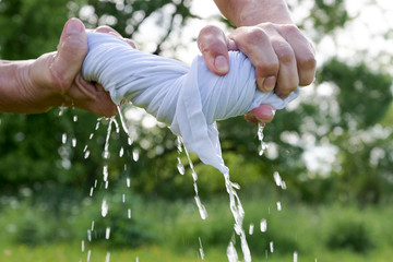 Hands squeeze wet cloth.