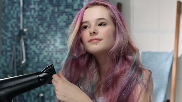 Young girl with pink hairs blow-dries her hair