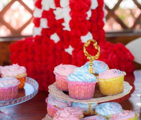 Multiple colorful nicely decorated muffins on a wooden background, top view.