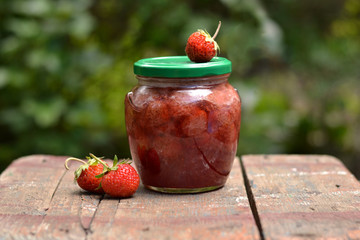 Homemade strawberry jam on a wooden table.