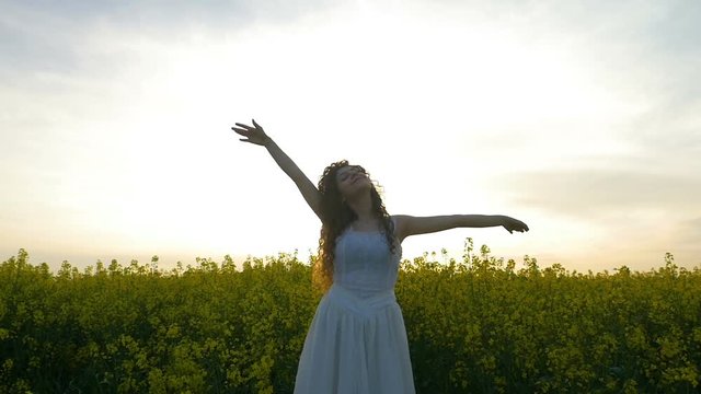 Concept of freedom with woman in nature holding hands towards the summer sky in the rapeseed field