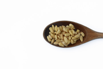 Pine nuts in wooden spoon isolated on white background.