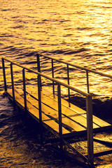 Golden sunset over sea, pier on the sea in evening