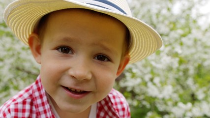 Portrait of little boy in the spring garden. Blooming tree on the background