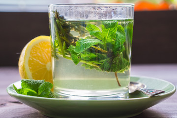tea with mint and a lemon on a dark table