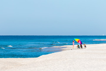 Fototapeta na wymiar Children on beach with colorful umbrella
