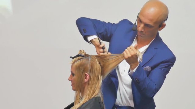 Hairdresser In Action. Barber and customers. hairstyle models for white hair. Blonde in the cabin. Work in the cabin. Barber shears white hair model client. close-up.