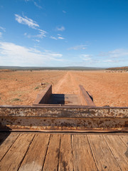 Rusty old Australian cattle truck  driving in a sun drenched arid landscape. A rusty cattle trailer...