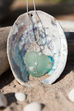Unique handmade aqua blue sea glass jewellery, with a silver chain in a sea shell.