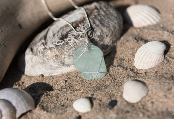 Unique handmade aqua blue sea glass jewellery, with a silver chain resting on a sea shell. © dannyburn