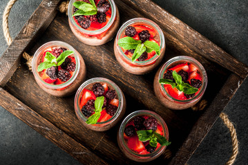 Healthy vegan breakfast. Dessert. Alternative food. Pudding with chia seeds, fresh strawberries, blackberries and mint. On a dark stone background, in an old wooden tray. Top view