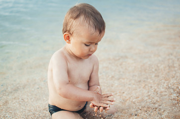 Fototapeta na wymiar The boy in the sea with sand in hands