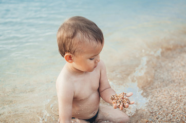 The boy in the sea with sand in hands