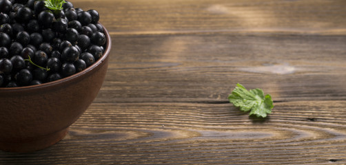 Obraz na płótnie Canvas Black currant on wooden table with leaf sprig