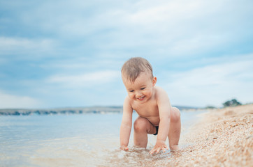 A child sitting in the sea near the shore, gazing into the distance and wonders