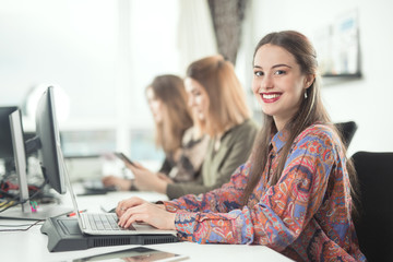 Portrait of cheerful young businesswoman working at her desk