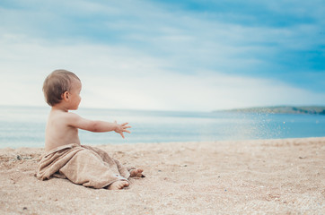 Fototapeta na wymiar The baby in a towel on the beach