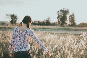Beautiful asian feeling sad because broken heart and she use hand touch grass flower on grass...