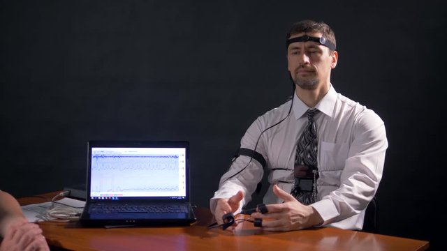 A man connected to polygraph deeply breathing and answering.