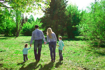 Naklejka na ściany i meble A family of four walks in the park.