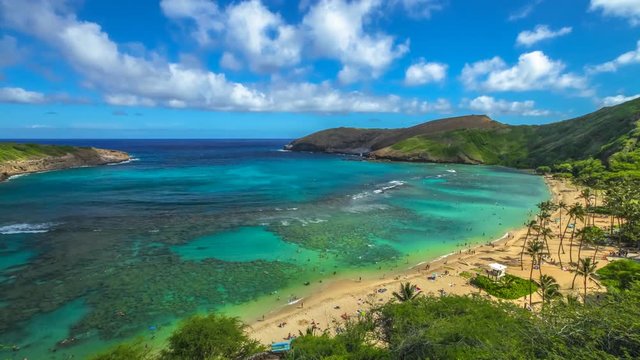 Aerial view time lapse with moving clouds above the beach with coral reef in famous Hanauma Bay Nature Preserve, Oahu island, Hawaii, United States. Summer time leisure and water sports recreation.