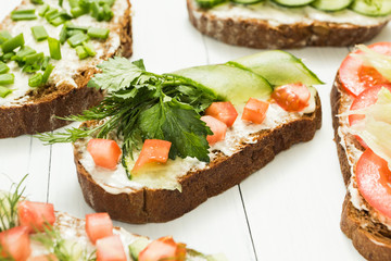 Assortment of vegetarian sandwiches with vegetables and cheese on a white table. Selective focus.