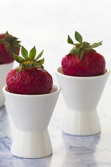 Bright ripe strawberry on a light marble background.