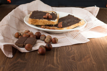 toast with peanut butter on a plate on the table with hazelnuts