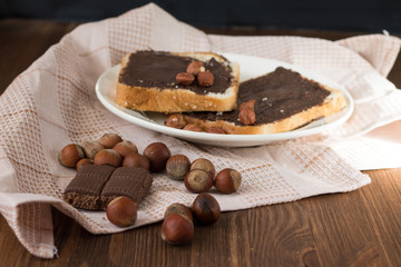 toast with peanut butter on a plate on the table with hazelnuts
