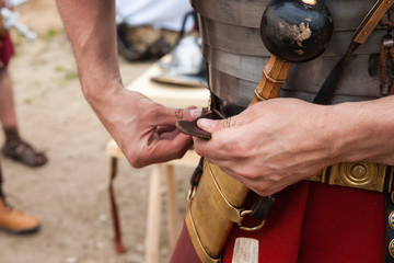 Roman soldier fastens war belt