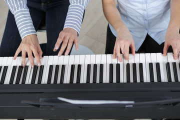 piano keyboard top view and hands of two players