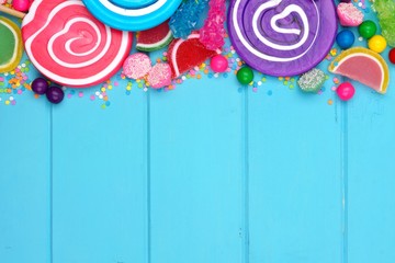 Top border of assorted colorful candies against a blue wood background - Powered by Adobe