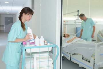 female nurse tiding up trolley in hospital hallway