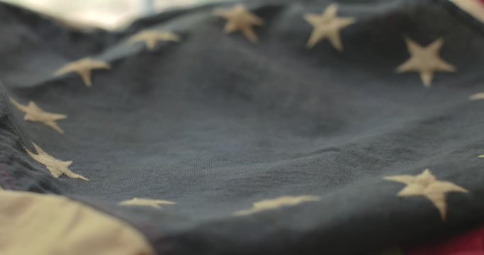 American flag detail with red and white stripes with field of blue and circle of 13 stars, the flag designed by Betsy Ross during the American Revolution. Shot in cinematic 4K.