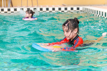 Two little girls swimming in swimming pool,they children so happy,bright sunlight,sunny day